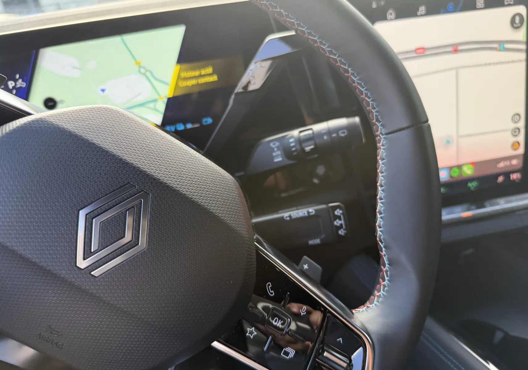 Vue rapprochée du volant noir avec surpiqûres tricolores et tableau de bord numérique du Renault Austral Hybrid 2025.