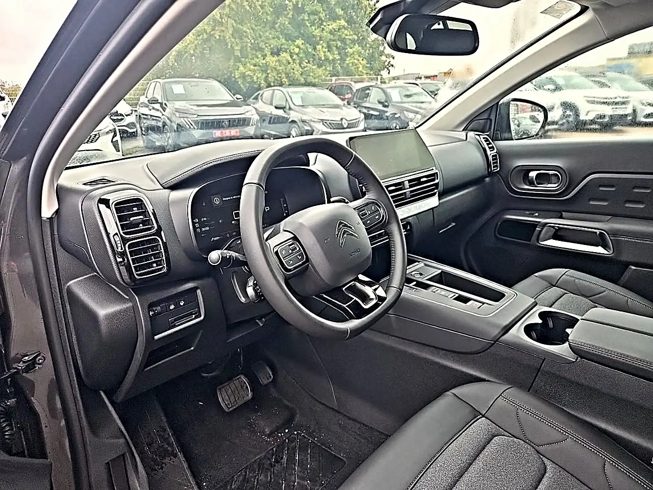 Vue intérieure côté conducteur du Citroën C5 Aircross gris, volant cuir multifonction et écran tactile central visible.