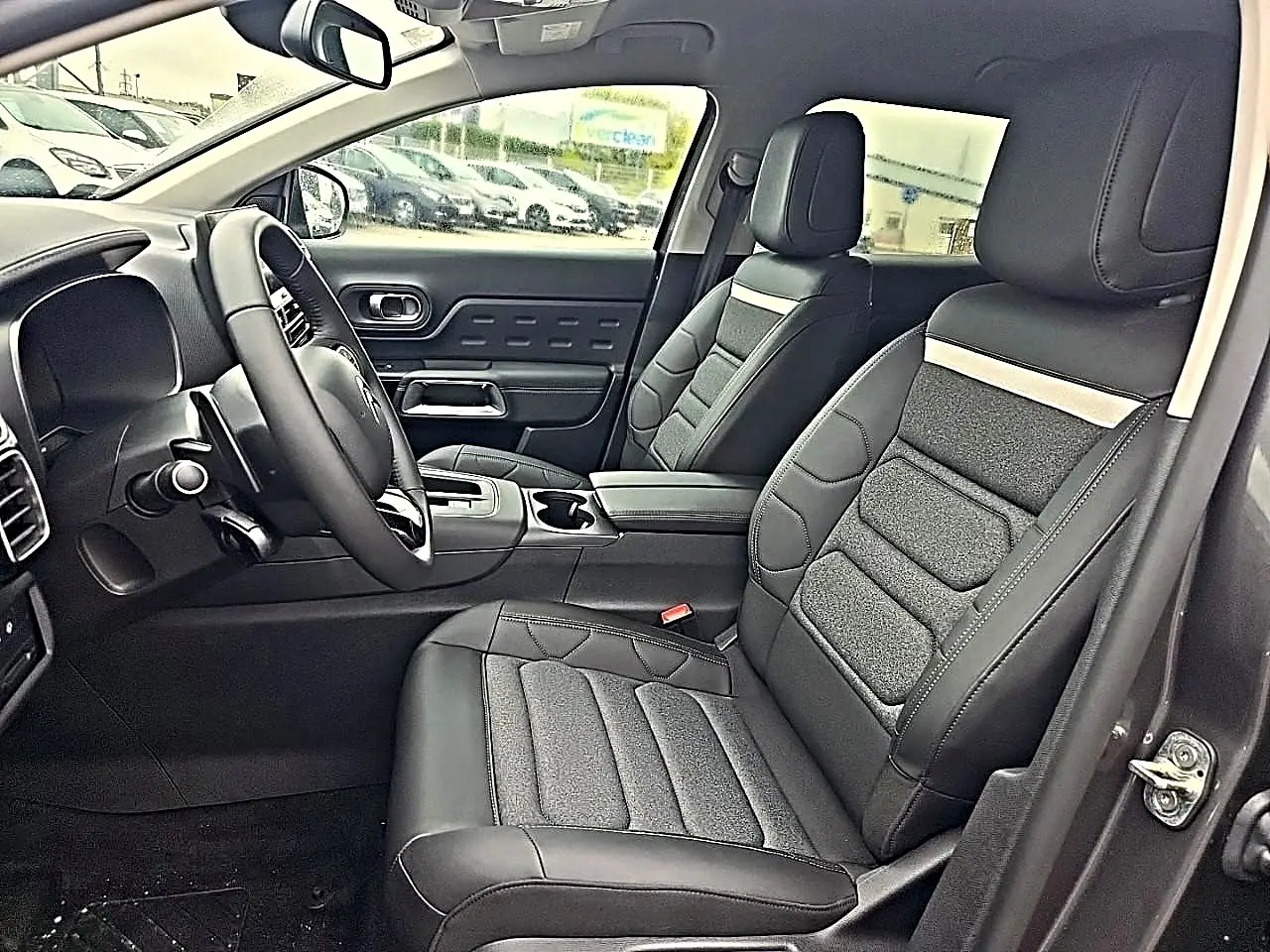 Intérieur avant du Citroën C5 Aircross gris, vue côté conducteur avec sièges en cuir noir et tissu gris.