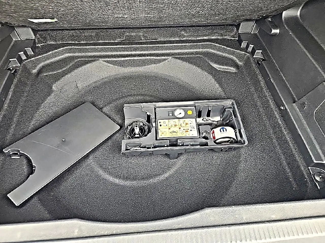 Vue plongeante sur le coffre gris du Citroën C5 Aircross 2025, montrant le rangement sous plancher avec kit de réparation.