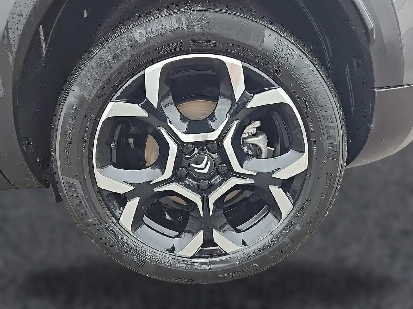 Gros plan sur la jante alu bicolore noire et argent du Citroën C5 Aircross gris, mettant en valeur le logo Citroën central.