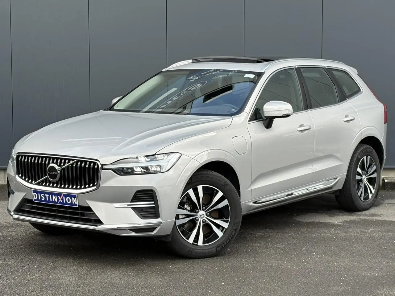 Volvo XC60 T6 AWD PHEV gris silver en 3/4 avant droit avec jantes alliage et toit ouvrant panoramique.