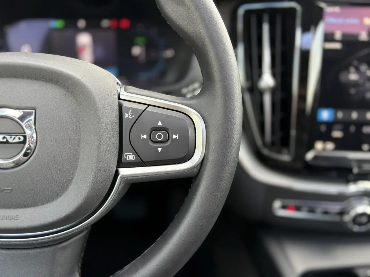 Gros plan sur le volant simili-cuir et les commandes multifonctions du Volvo XC60 T6 AWD PHEV 2024.