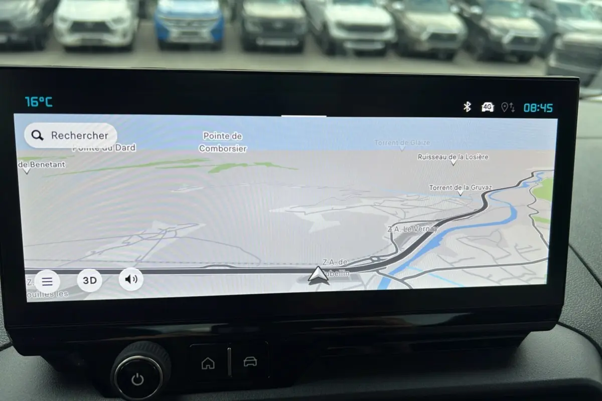 Écran tactile du système de navigation du Citroën Berlingo 2025, avec vue sur parking flou en arrière-plan.