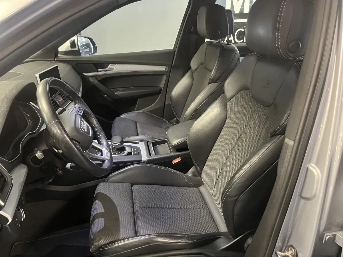 Vue intérieure côté conducteur de l'Audi Q5 S line 2019, sièges sport en cuir noir avec volant multifonction.