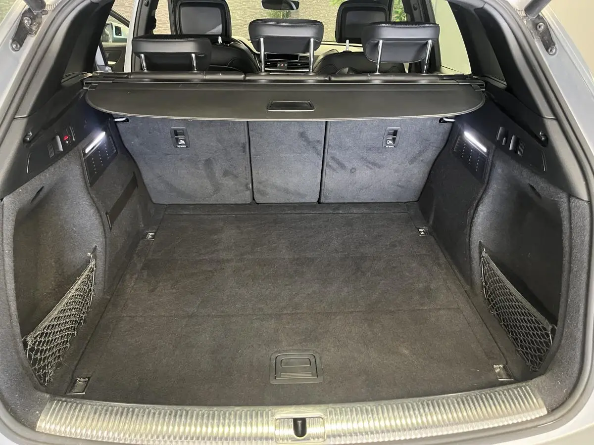 Coffre spacieux de l'Audi Q5 gris 2019 vu de l'arrière avec banquette rabattable et filets latéraux.