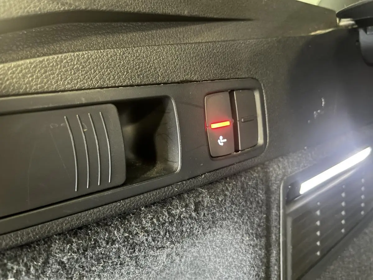 Gros plan sur le bouton de rabattement électrique des sièges dans le coffre d'un Audi Q5 gris S line 2019.