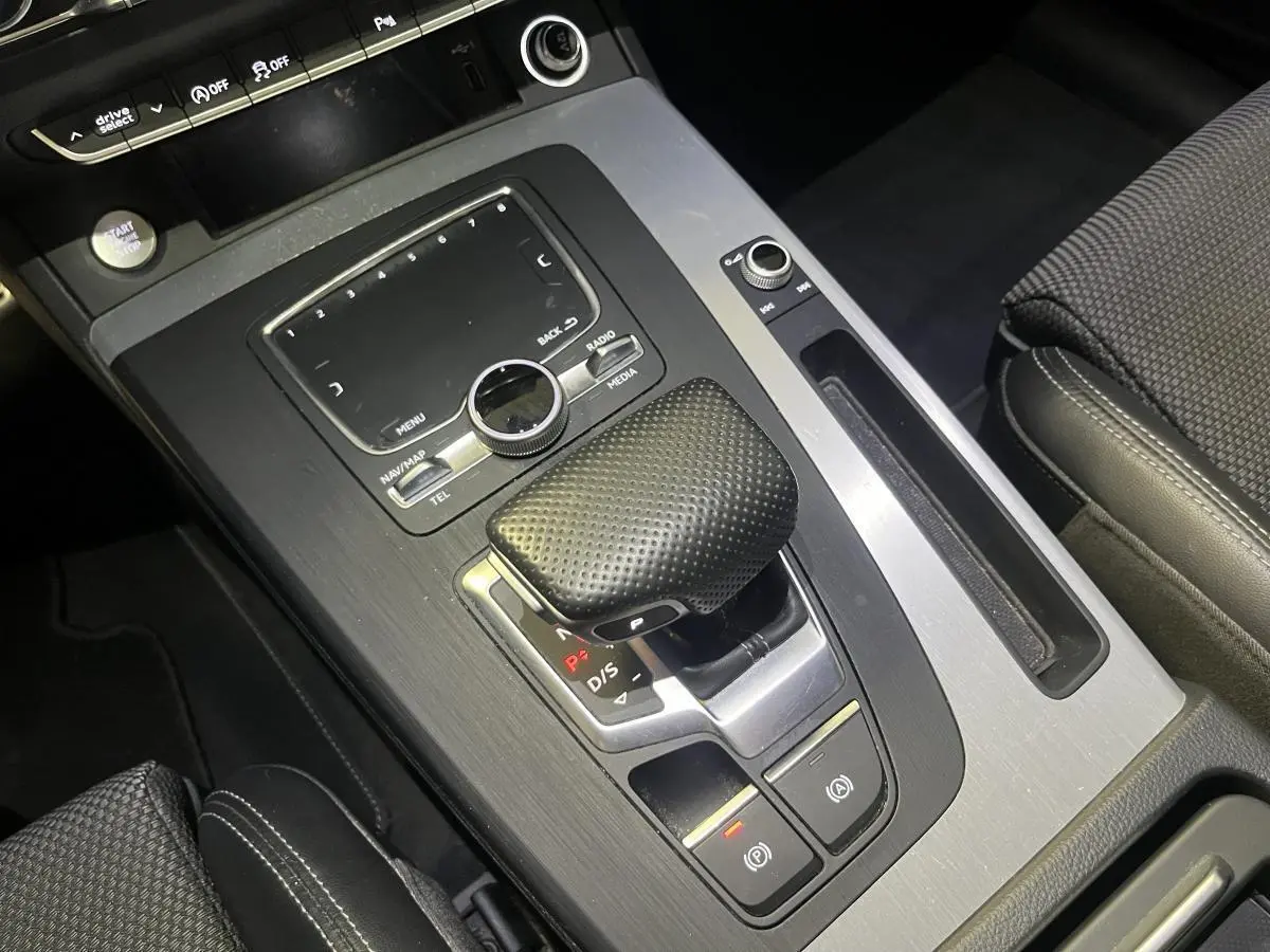 Vue rapprochée de la console centrale grise de l'Audi Q5 S line 2019 avec levier de vitesse et commandes multimédia.