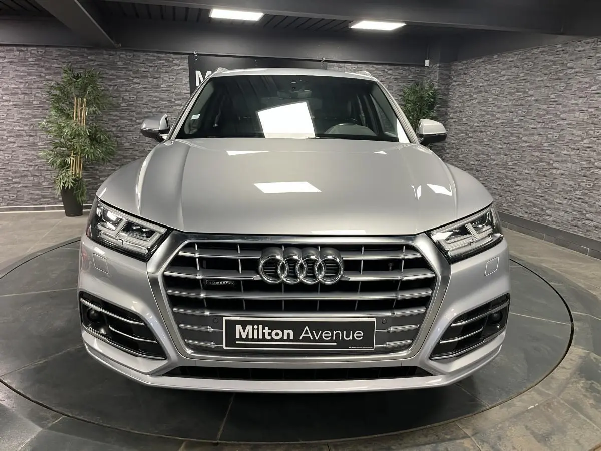 Vue frontale d'un Audi Q5 gris métallisé avec calandre S line et phares à LED dans un showroom.
