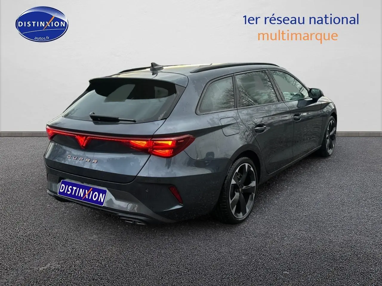 Vue 3/4 arrière droite d'une CUPRA Leon ST gris magnétique avec feux arrière LED allumés et jantes alliage noires.