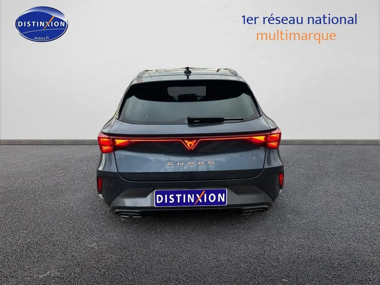 Vue arrière d'une CUPRA Leon ST gris magnétique avec feux LED allumés et double sortie d'échappement visible.