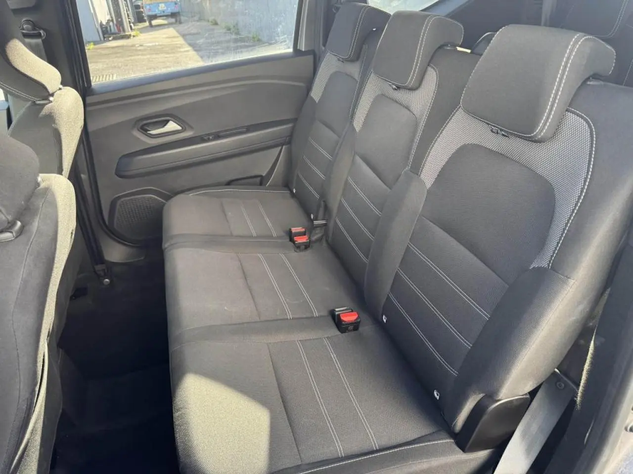 Vue intérieure côté droit sur la banquette arrière noire du Dacia Jogger 2025 avec appuie-têtes et ceintures visibles.