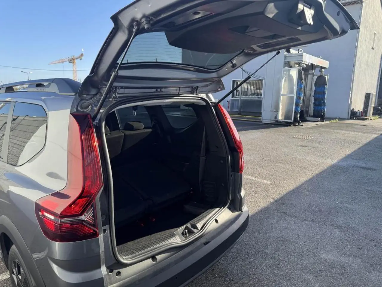 Vue arrière ouverte en 3/4 droit d'un Dacia Jogger gris schiste métal avec feux arrière LED distinctifs.