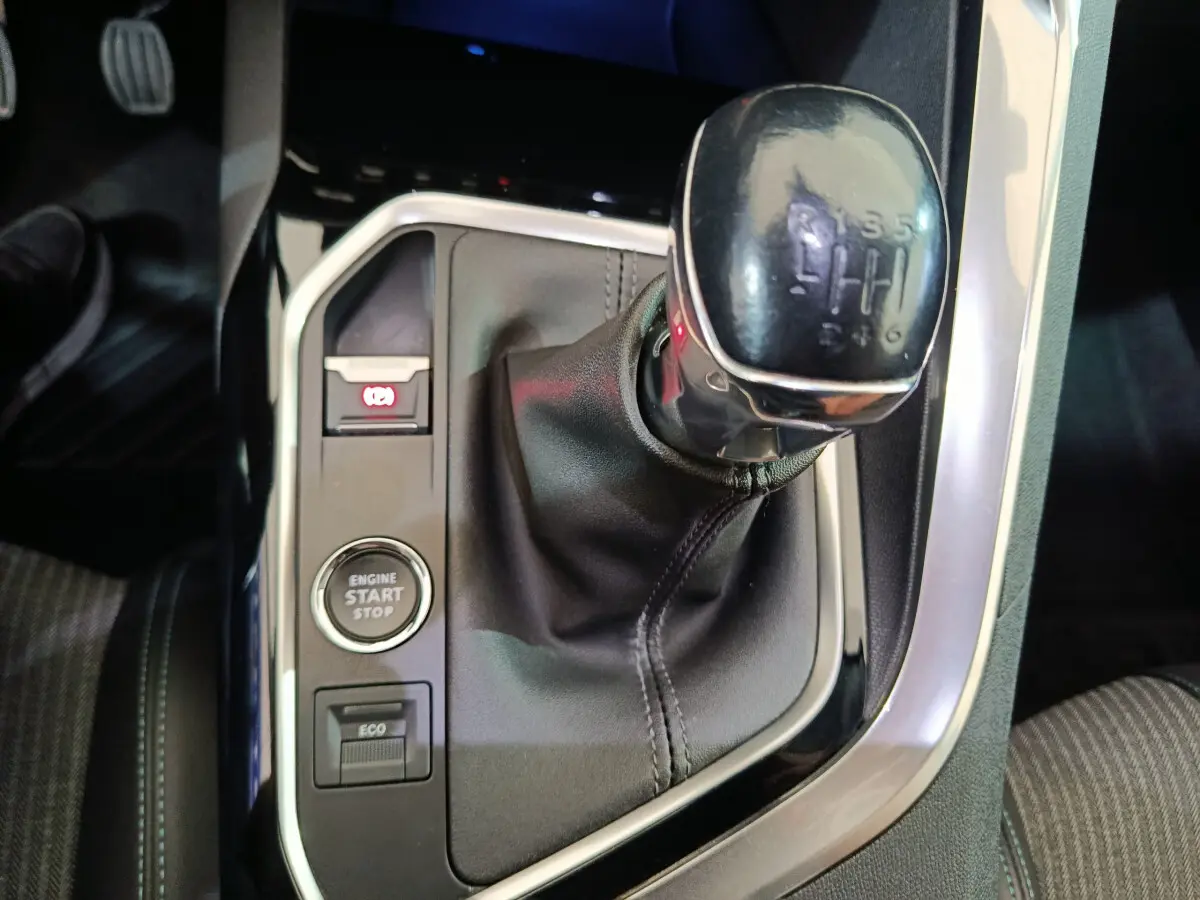 Gros plan sur la console centrale du Peugeot 3008 bleu 2022, mettant en valeur le levier de vitesse manuel et le bouton start/stop.