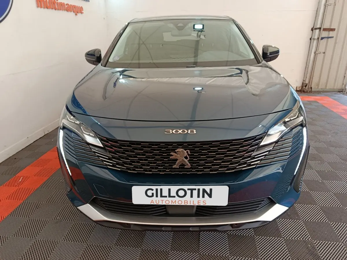 Vue frontale d'un Peugeot 3008 bleu 2022 avec calandre noire et feux LED distinctifs allumés.