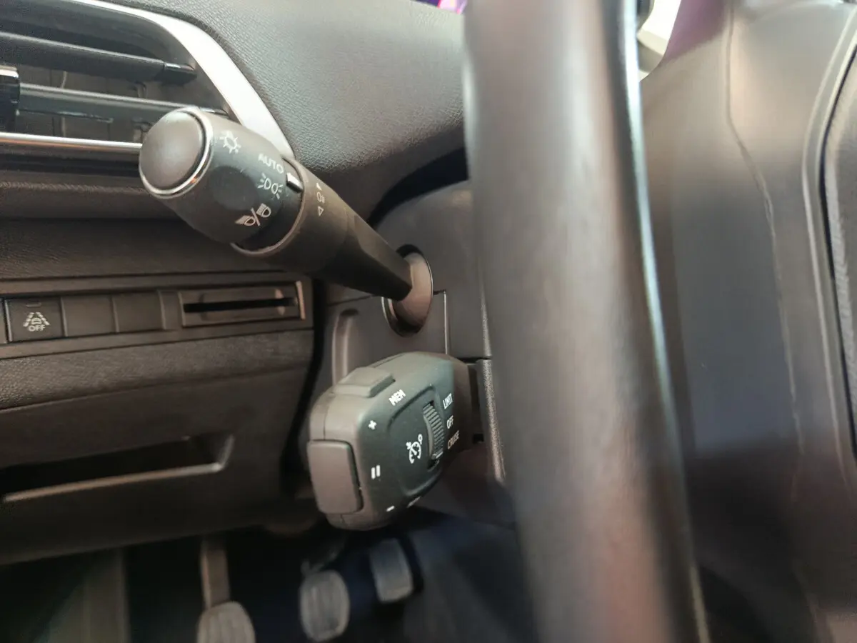 Gros plan sur la manette de commande des feux et régulateur de vitesse côté gauche du volant cuir du Peugeot 3008 bleu 2022.