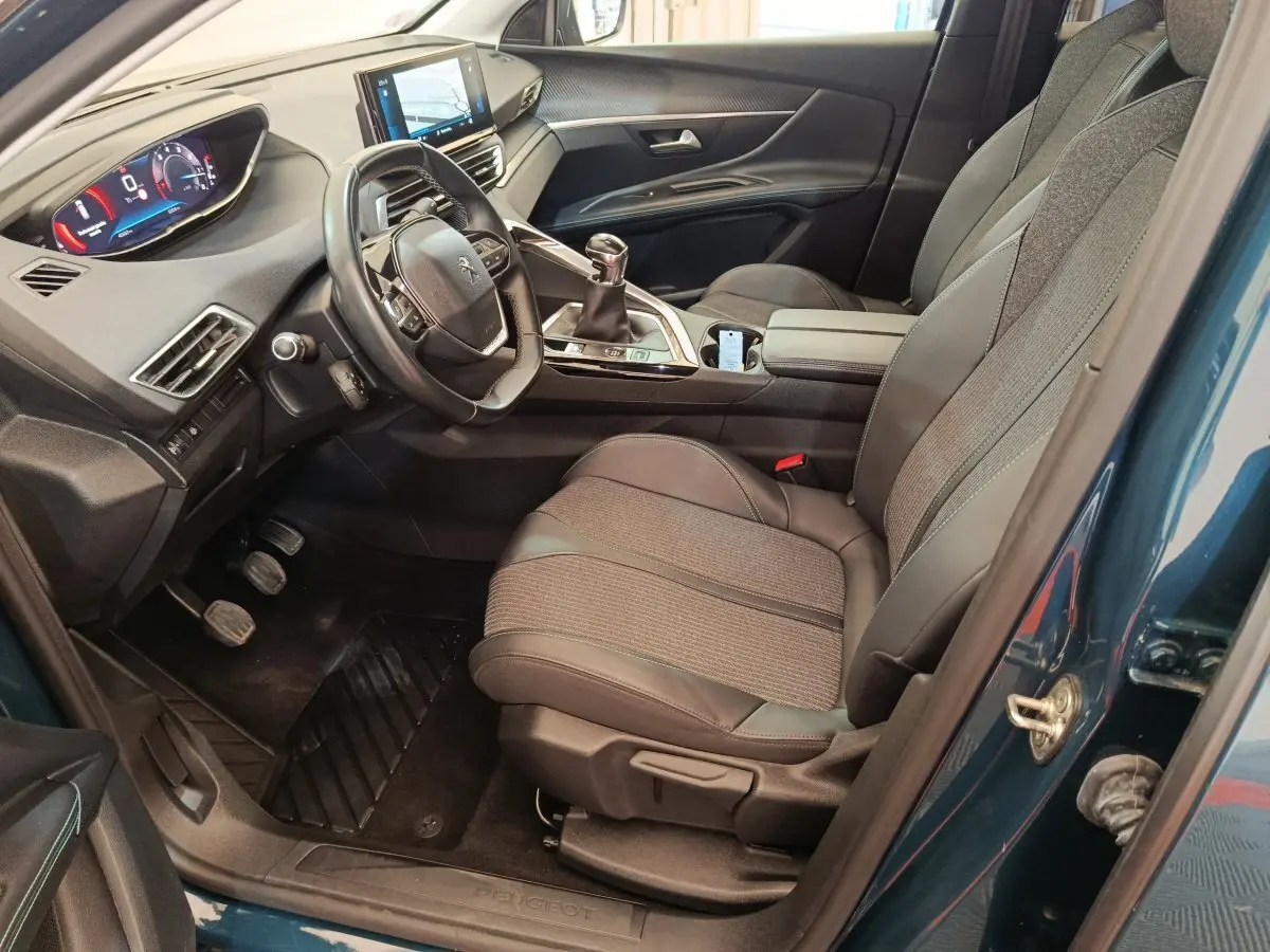 Intérieur avant gauche du Peugeot 3008 bleu 2022, volant cuir, tableau de bord numérique et console centrale moderne.