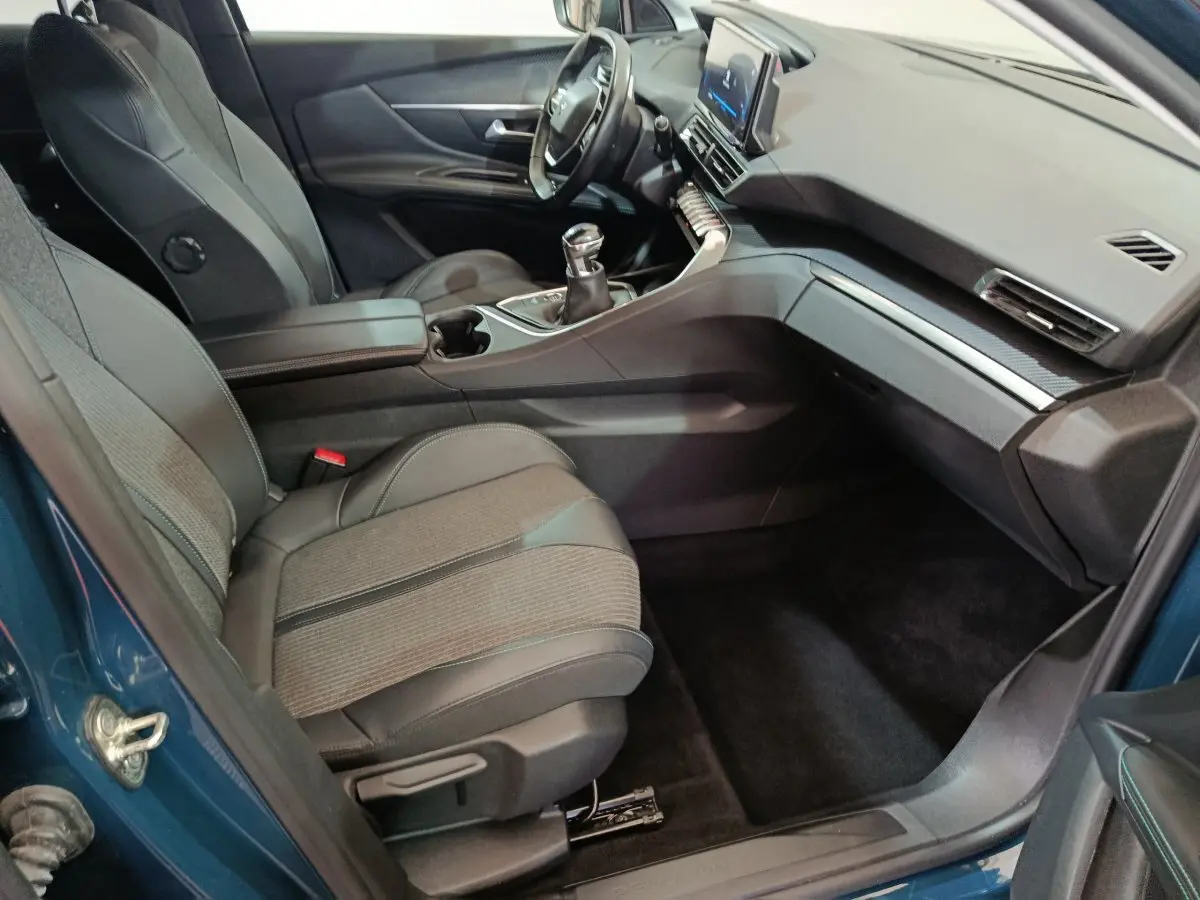 Intérieur avant droit du Peugeot 3008 bleu 2022, sièges tissu et cuir, tableau de bord moderne avec écran tactile central.