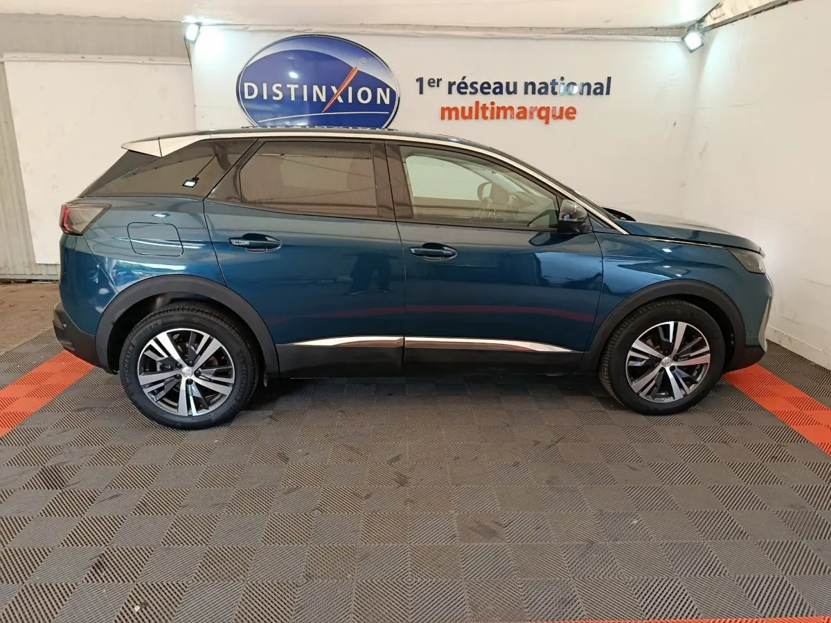 Profil côté droit d'un Peugeot 3008 bleu 2022 garé en intérieur sur sol damier noir et rouge.