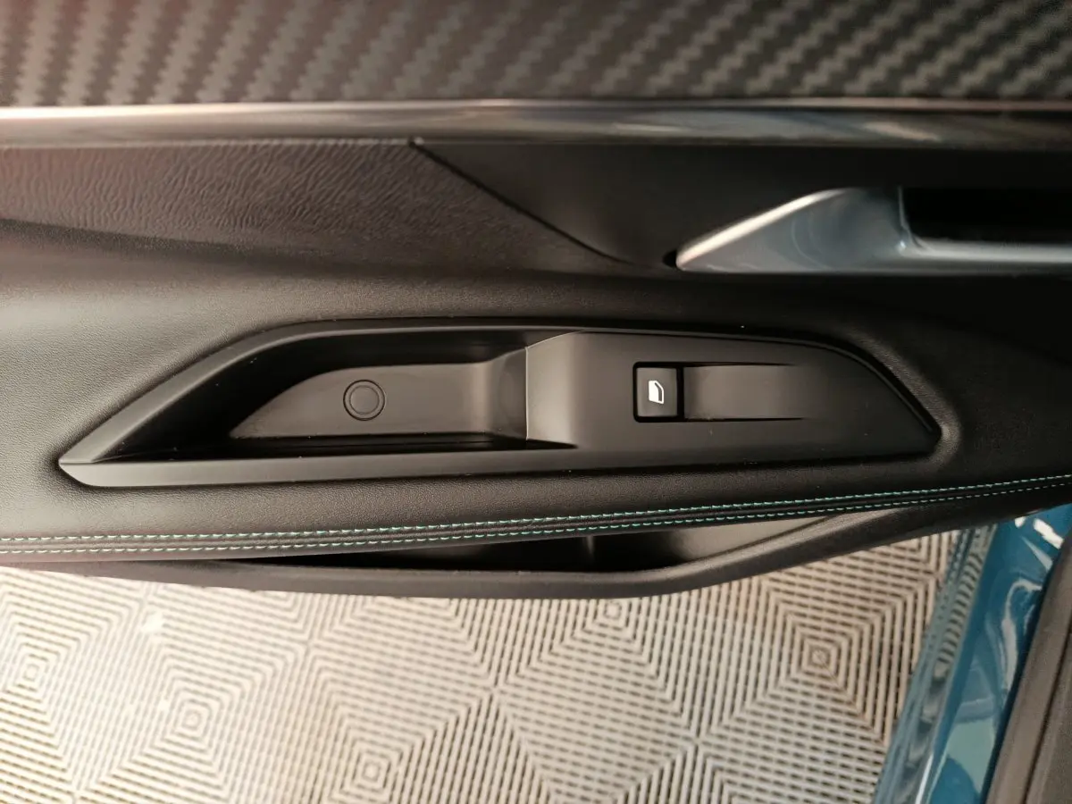 Gros plan sur la poignée intérieure côté gauche de la porte d’un Peugeot 3008 bleu avec surpiqûres bleues.