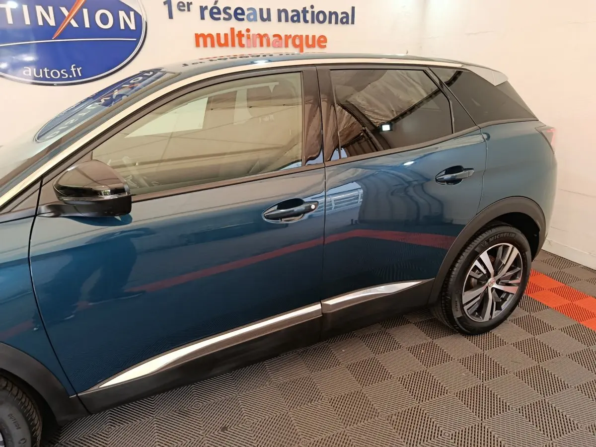 Vue latérale côté gauche du Peugeot 3008 bleu avec jantes alliage et toit noir en intérieur showroom.