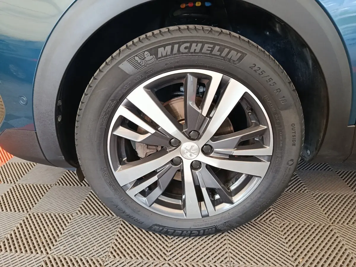 Gros plan sur la roue avant gauche du Peugeot 3008 bleu, mettant en valeur la jante alliage et le pneu Michelin.