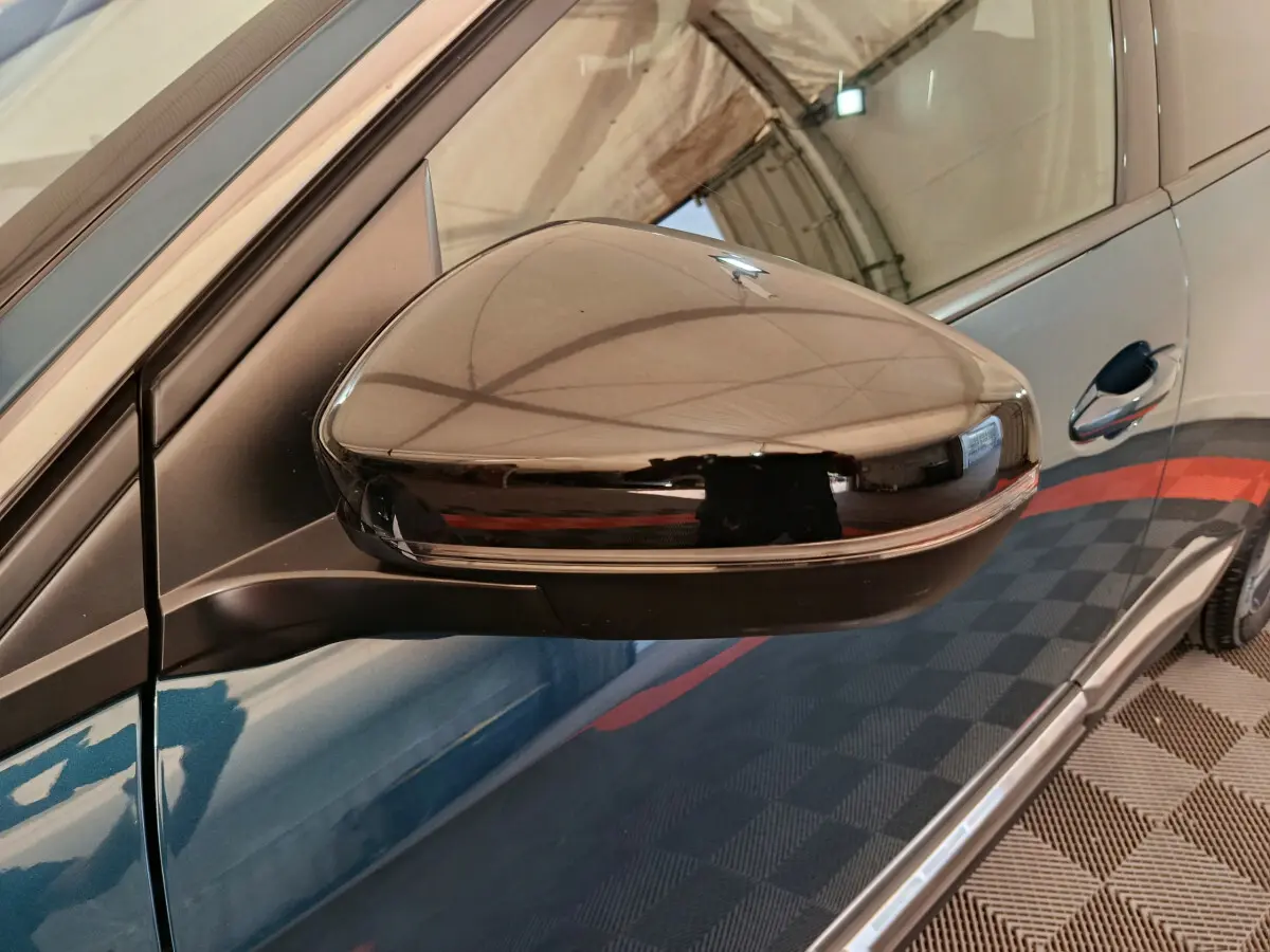 Rétroviseur côté gauche noir brillant du Peugeot 3008 bleu, vue rapprochée sur la portière avant.