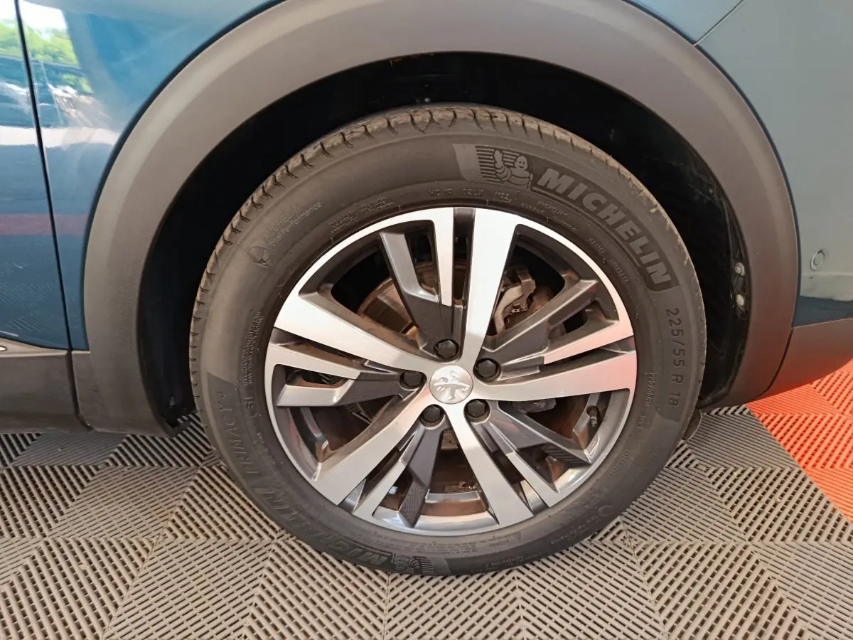 Gros plan sur la roue avant gauche bleu du Peugeot 3008 avec jante alliage et pneu Michelin visible.