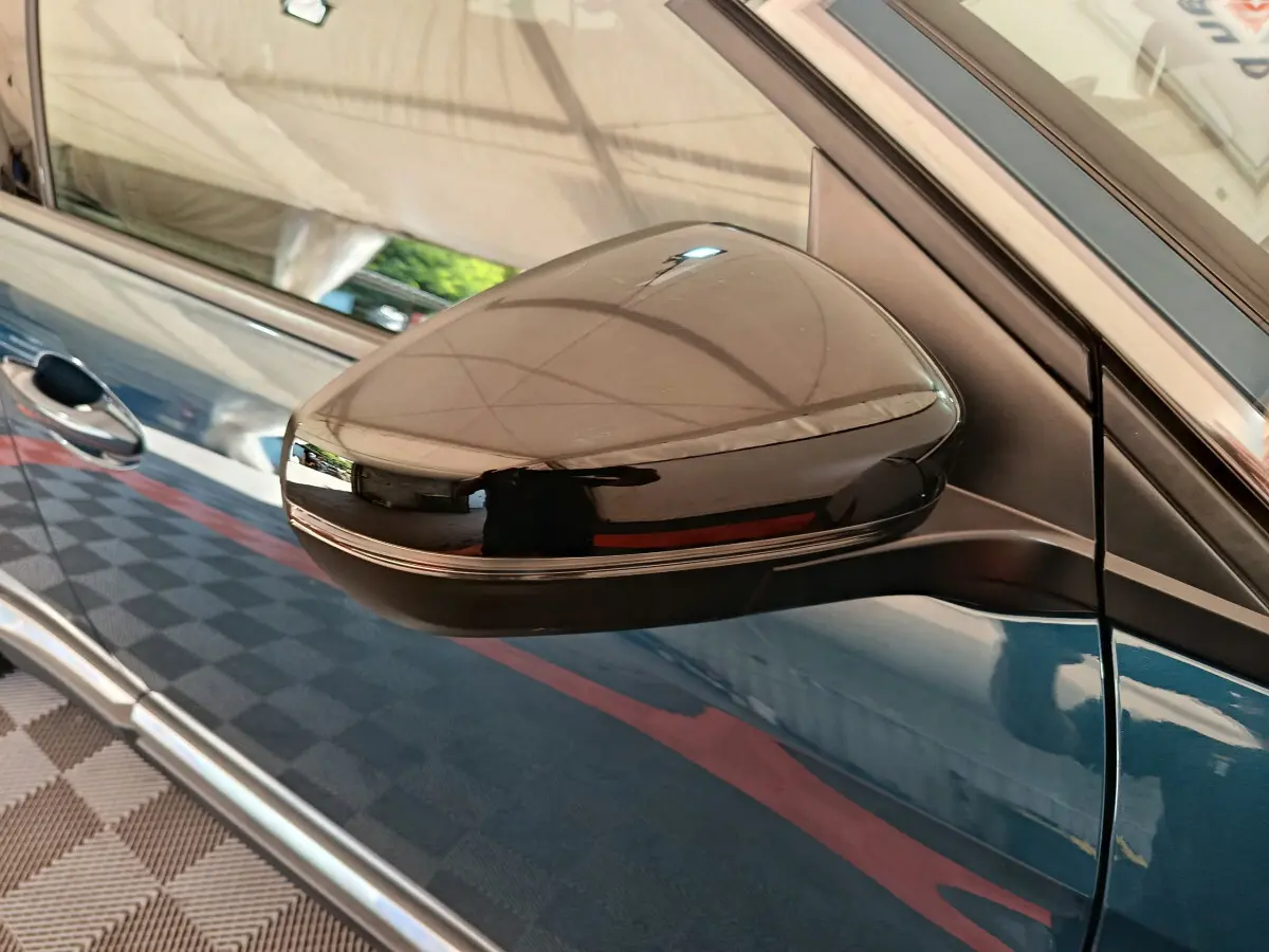 Gros plan sur le rétroviseur droit noir brillant du Peugeot 3008 bleu, avec reflet du plafond intérieur.