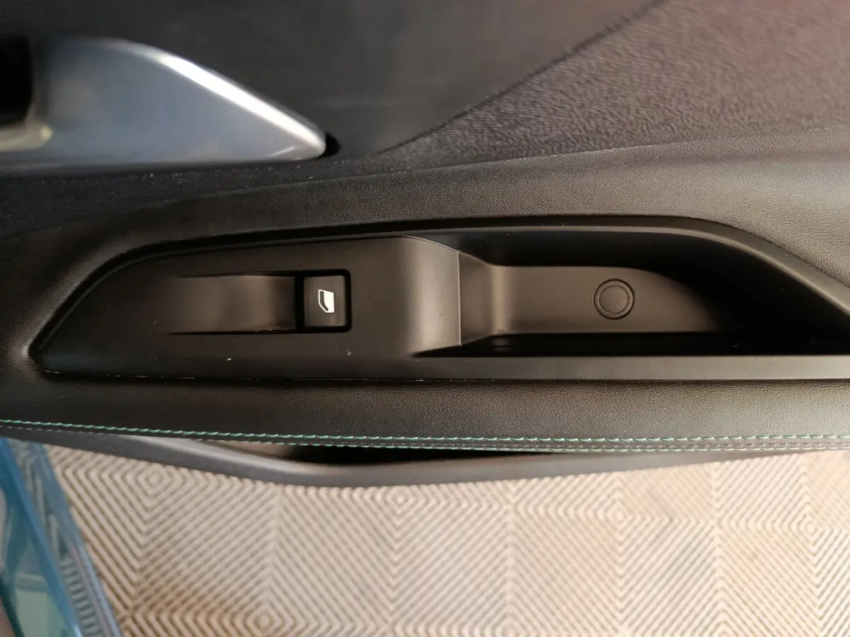 Détail de la commande de lève-vitre côté gauche sur la porte intérieure noire du Peugeot 3008 bleu 2022.
