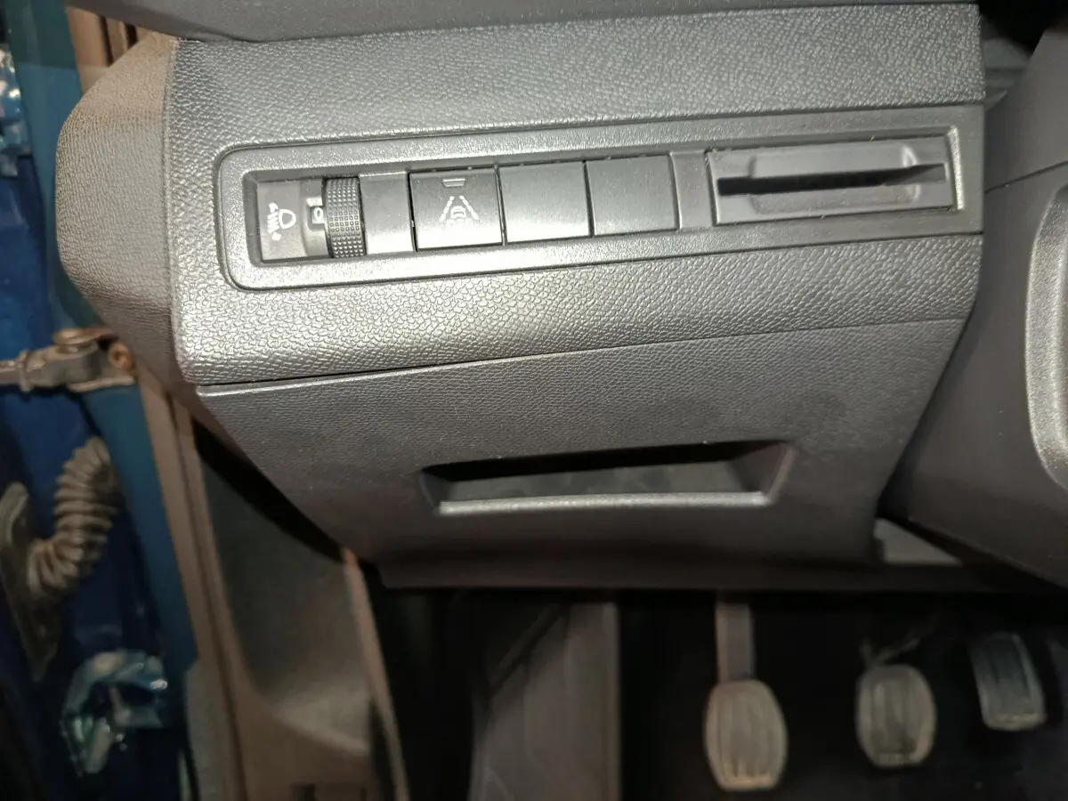 Gros plan sur les commandes de réglage des phares et aides à la conduite côté gauche d'un Peugeot 3008 bleu 2022.