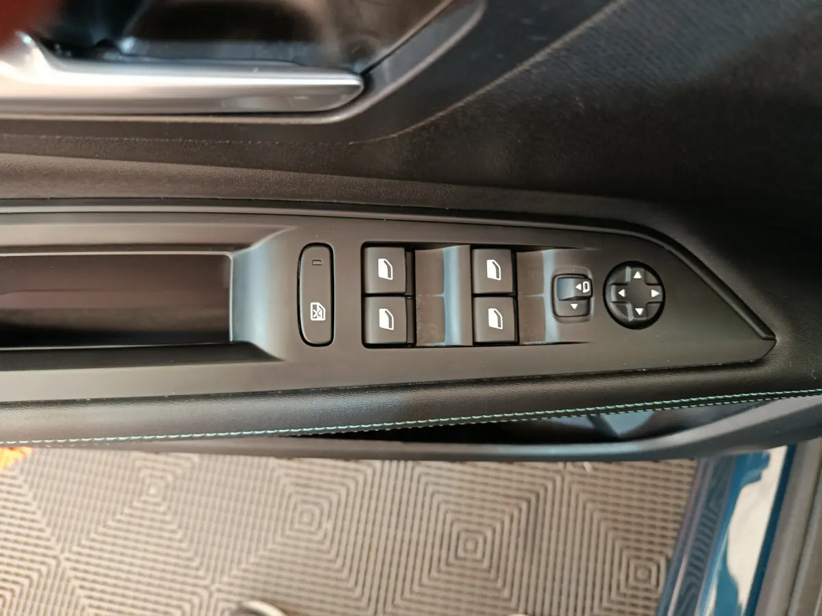 Panneau de commandes des vitres et rétroviseurs côté conducteur d’un Peugeot 3008 bleu, finition Allure 2022.