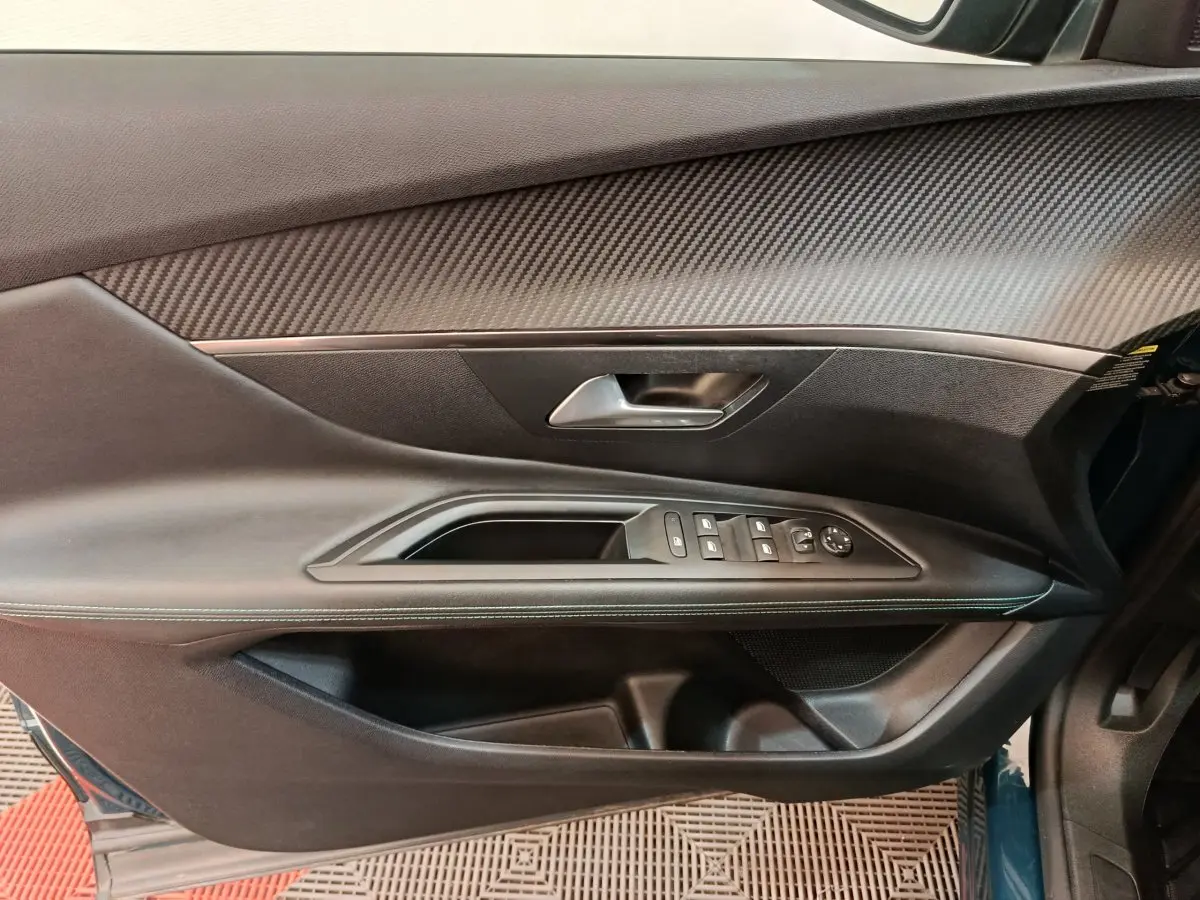 Gros plan sur la porte côté gauche du Peugeot 3008 bleu, montrant les commandes électriques et le revêtement noir texturé.