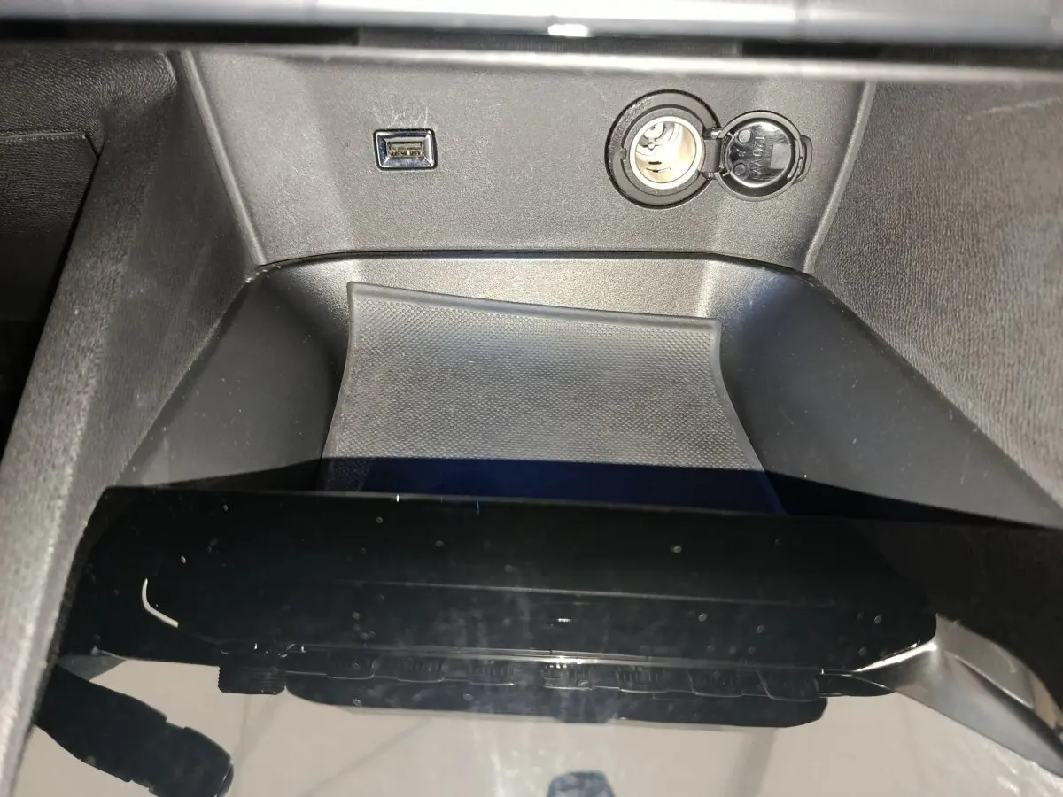 Gros plan sur la console centrale noire du Peugeot 3008 bleu, montrant prise USB et prise 12V ouverte.