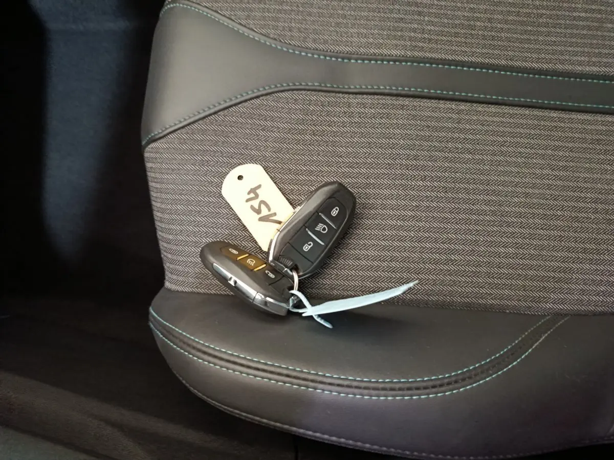 Gros plan sur les clés de la Peugeot 3008 PureTech 130 posées sur un siège tissu et cuir noir avec surpiqûres bleues.