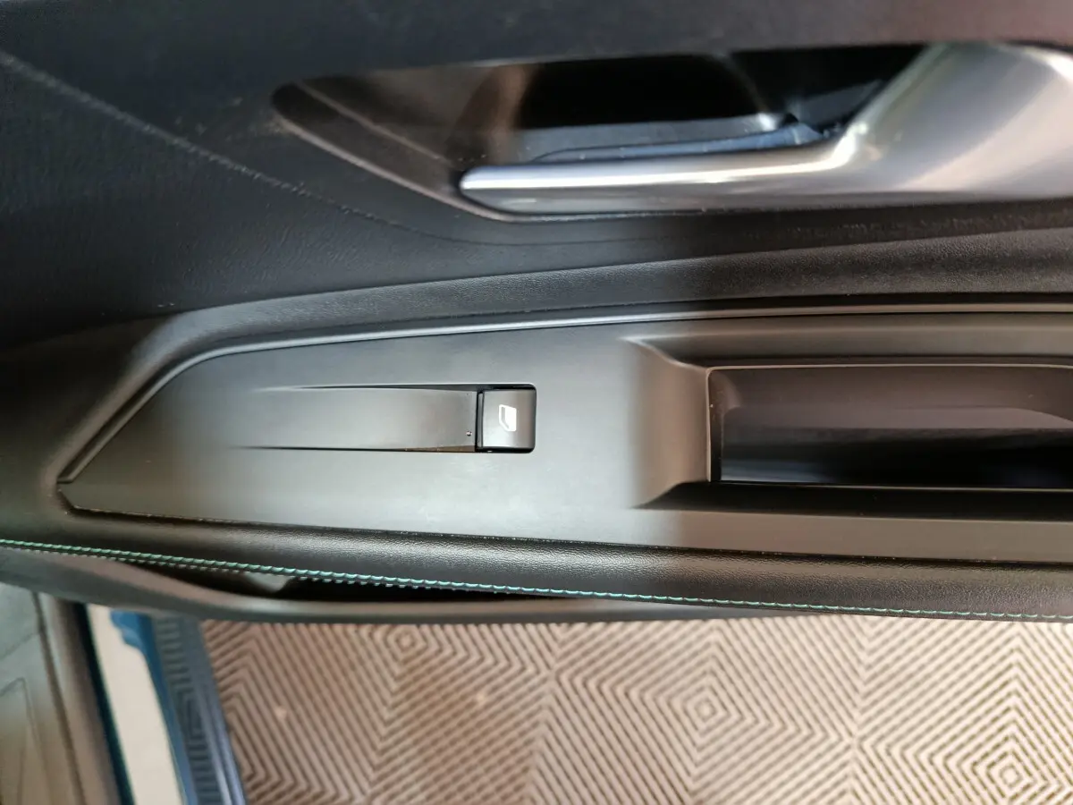 Gros plan sur la commande de lève-vitre côté conducteur dans l'intérieur noir du Peugeot 3008 PureTech 130 S&S Allure 2022.