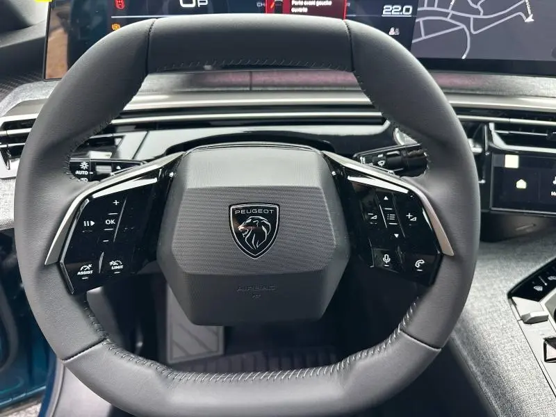 Volant cuir multifonction de Peugeot 3008 1.2 Hybrid bleu, vue frontale centrée sur le logo lion noir et chrome.