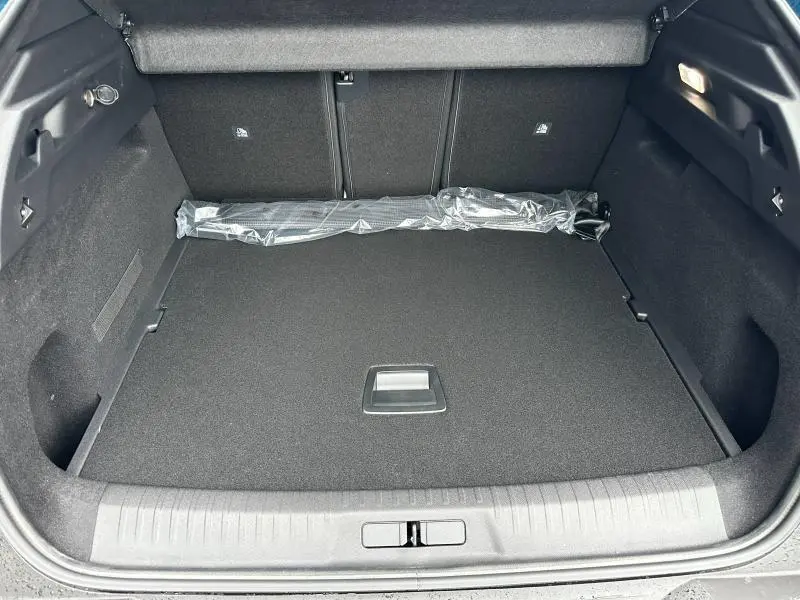 Coffre spacieux du Peugeot 3008 Hybrid 2025 vu de l'arrière, avec tapis noir et rangement sous plastique.