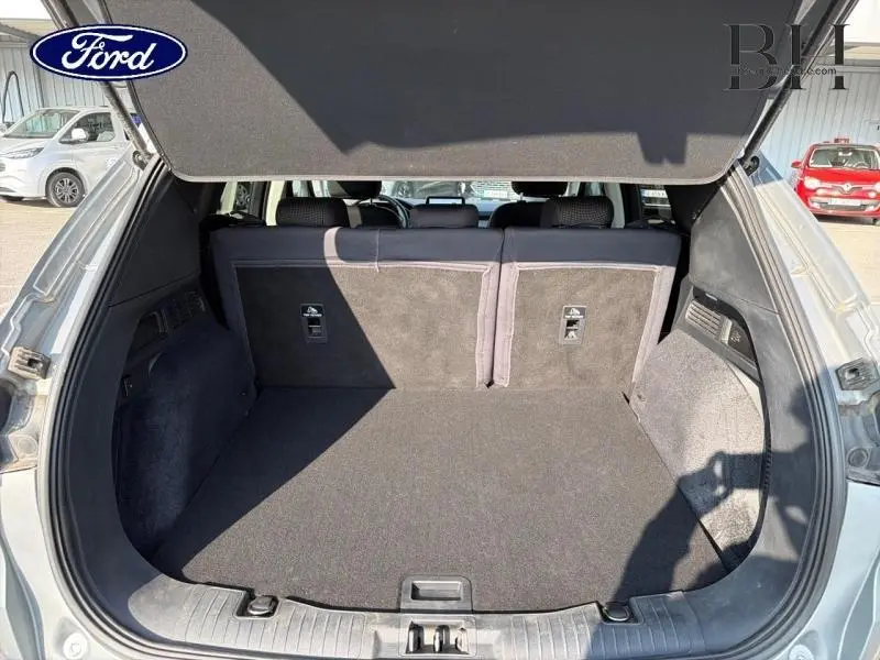 Coffre ouvert vu de l'arrière du Ford Kuga gris Solar Métallisée, montrant un espace de chargement propre et spacieux.