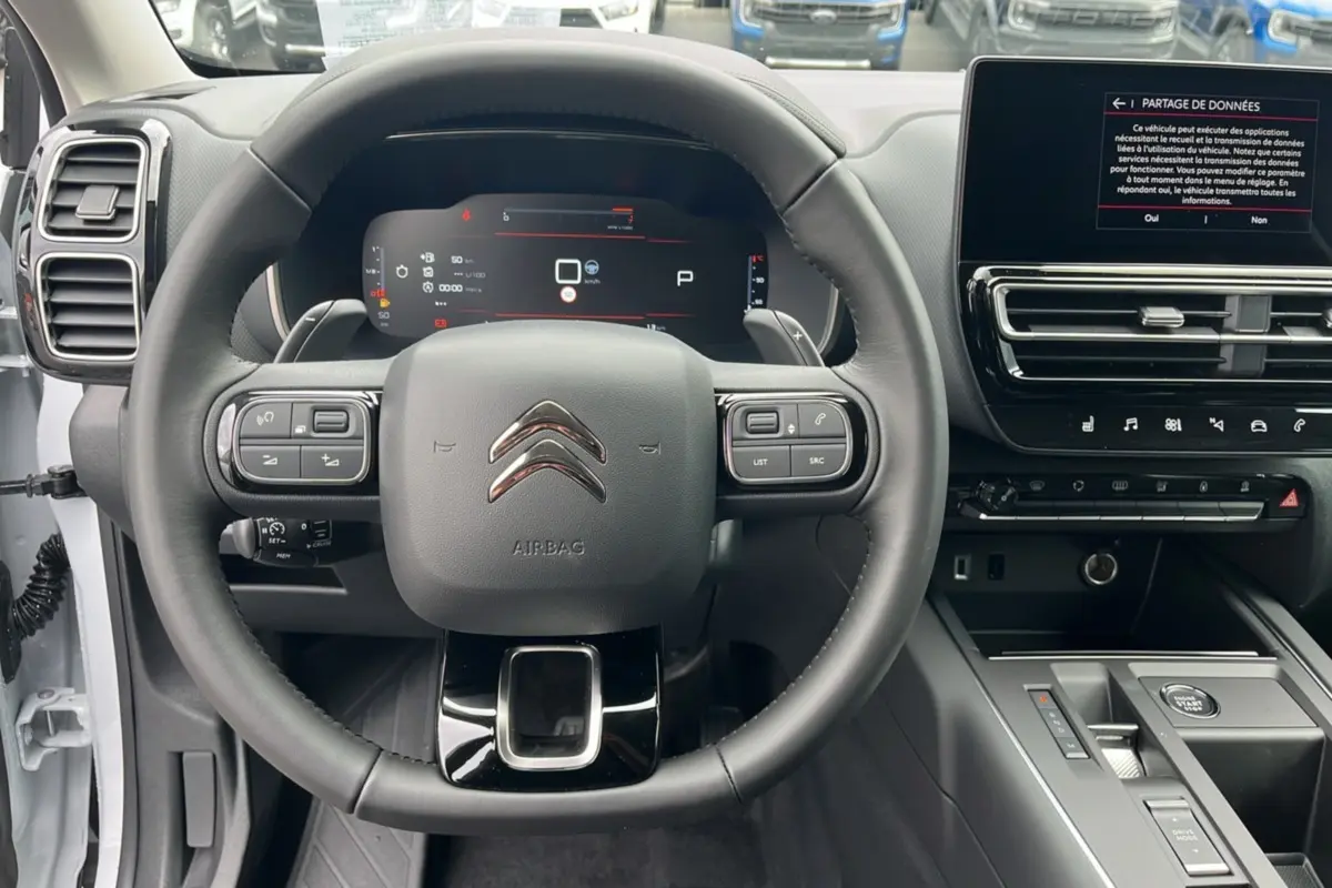 Vue frontale du volant cuir multifonctions et tableau de bord numérique du Citroën C5 Aircross blanc okénite 2025.