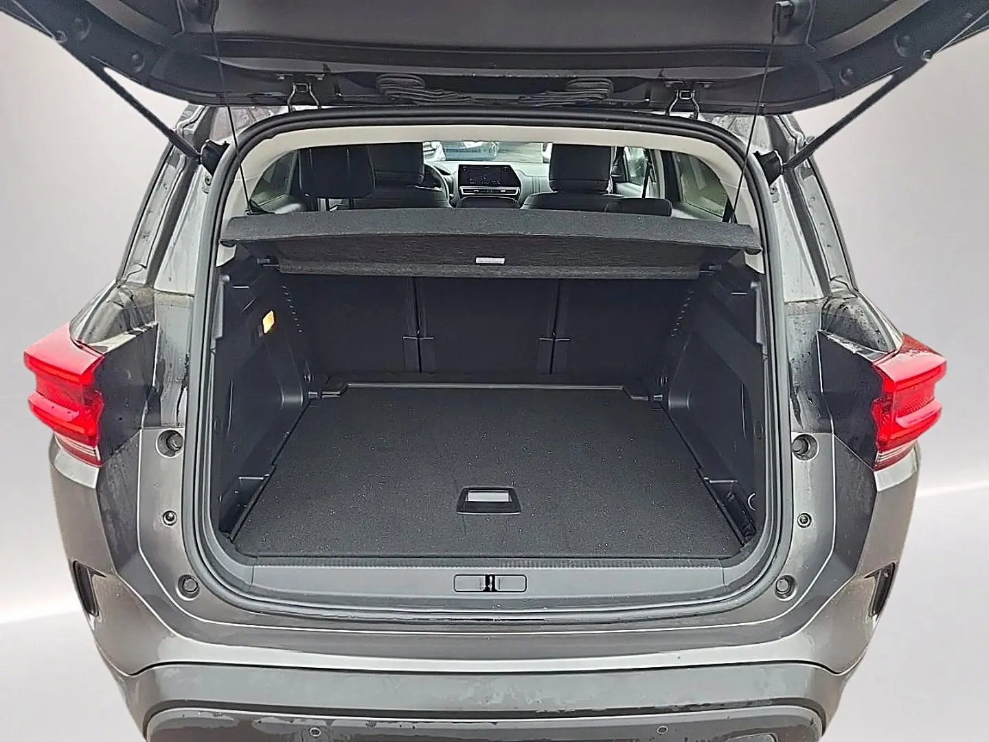 Coffre ouvert vu de l'arrière d'un Citroën C5 Aircross gris 2025 avec banquette arrière et tablette cache-bagages visibles.