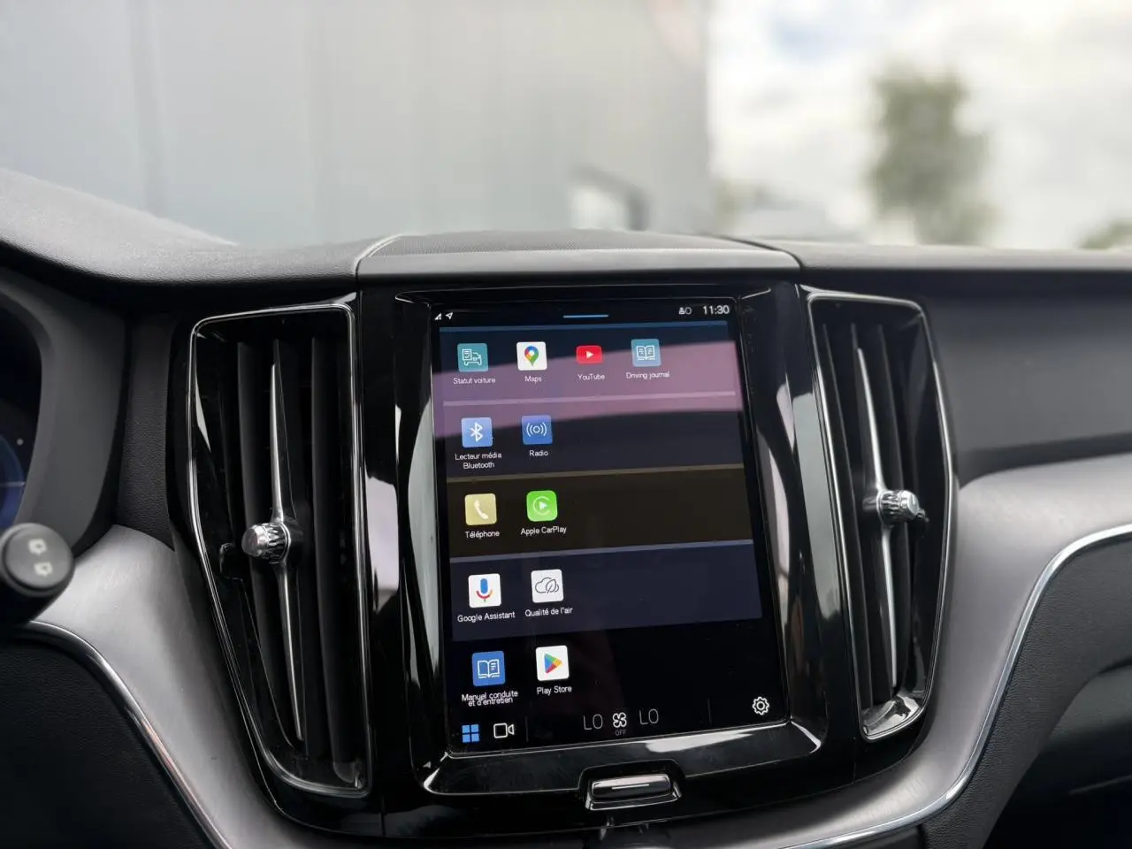 Écran tactile central 9 pouces du Volvo XC60 T6 AWD PHEV rouge, avec commandes multimédia et aérateurs noirs.