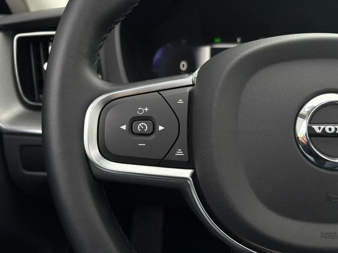 Gros plan sur le côté gauche du volant simili-cuir du Volvo XC60 T6 AWD PHEV 2024 avec commandes de régulateur de vitesse.