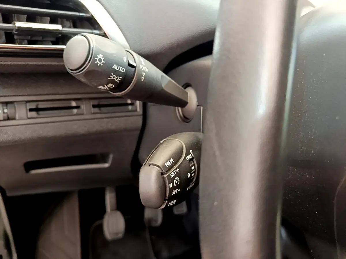 Gros plan sur les commandes au volant cuir du côté gauche du Peugeot 3008 gris foncé Puretech 130 S&S ACTIVE 2020.