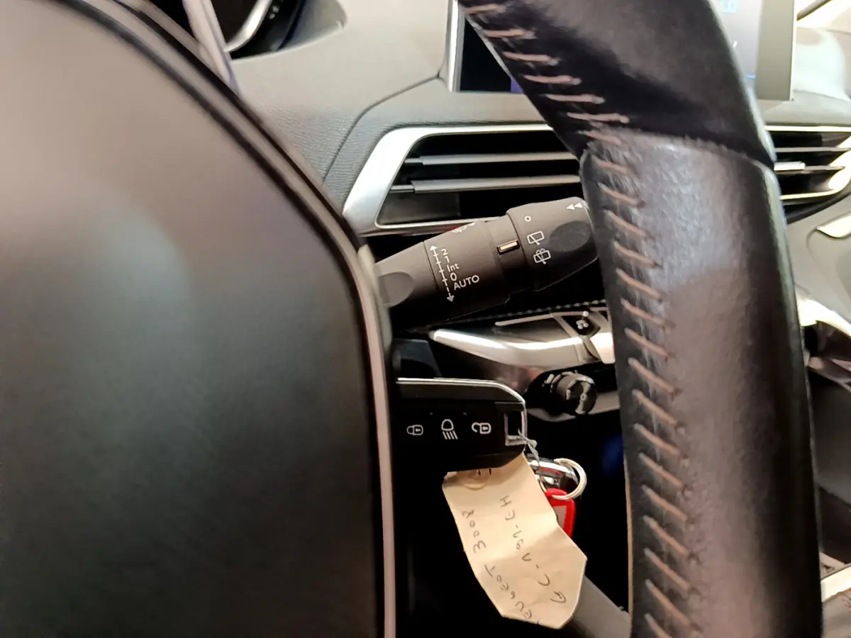 Gros plan sur le volant cuir et la commande d’essuie-glace du Peugeot 3008 gris foncé, version Puretech 130 S&S ACTIVE.