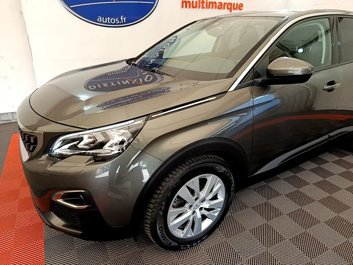 Peugeot 3008 gris foncé en 3/4 avant droit, avec phares LED et jantes alliage visibles en intérieur showroom.