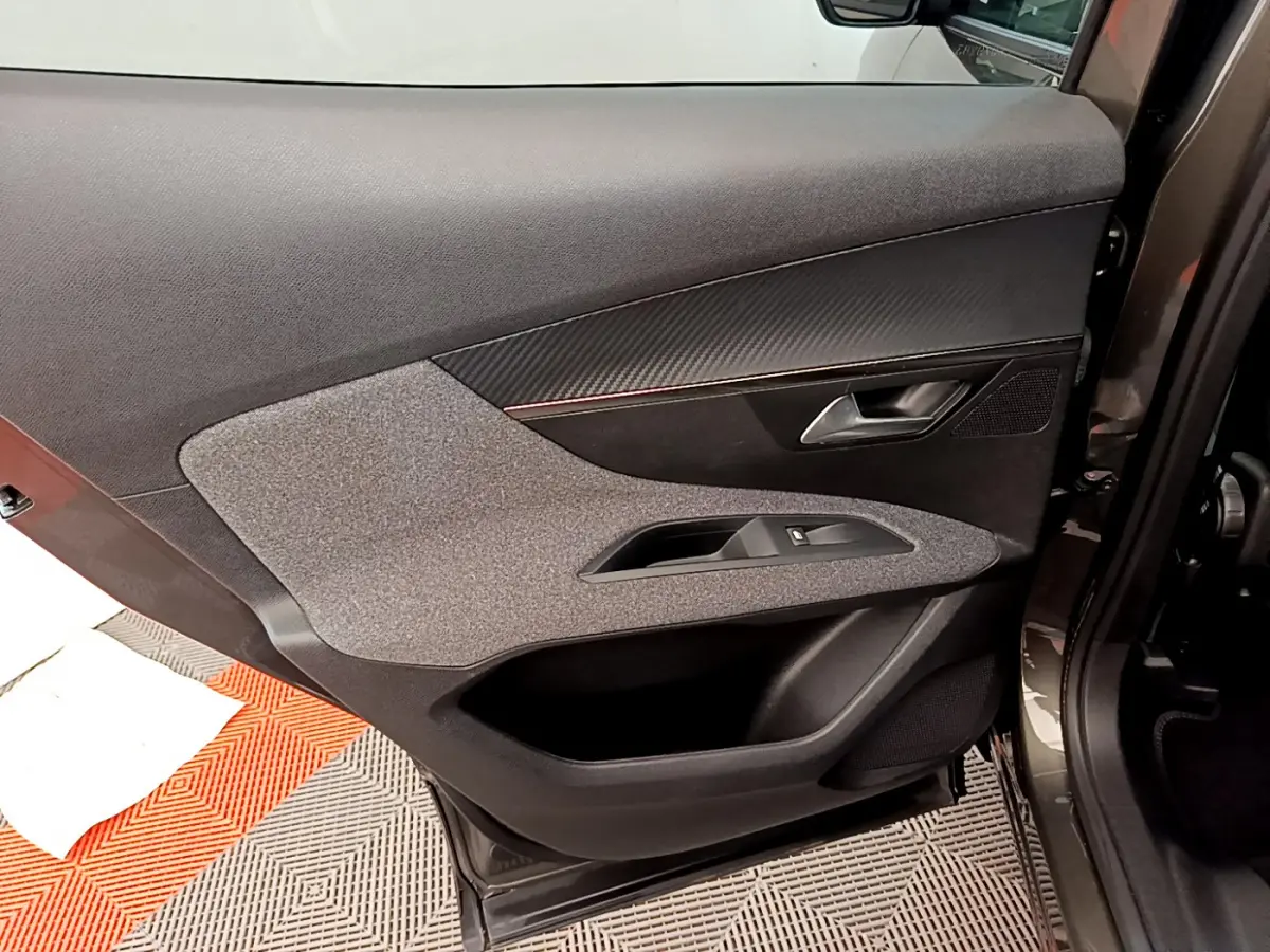 Vue intérieure côté gauche de la porte avant gris foncé du Peugeot 3008 avec garniture tissu et plastique noir.