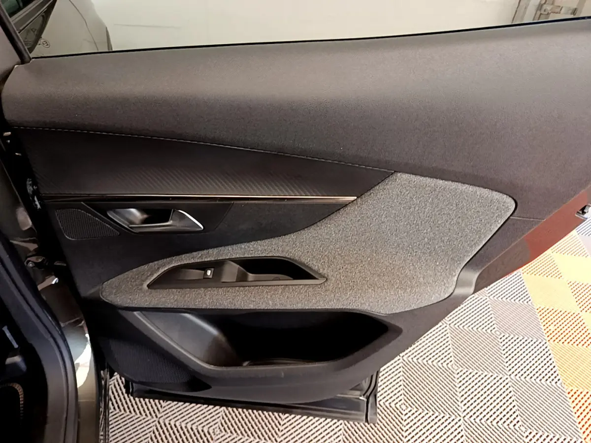 Vue rapprochée de la porte côté gauche du Peugeot 3008 gris foncé, avec garniture tissu et commandes de fenêtre intégrées.