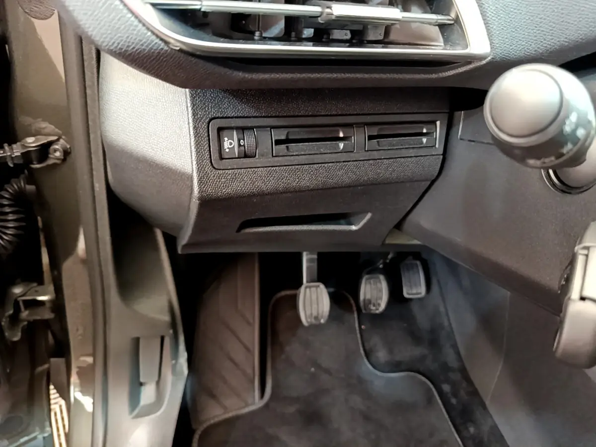Vue rapprochée côté gauche du poste de conduite du Peugeot 3008 gris foncé, avec pédales et commandes visibles.