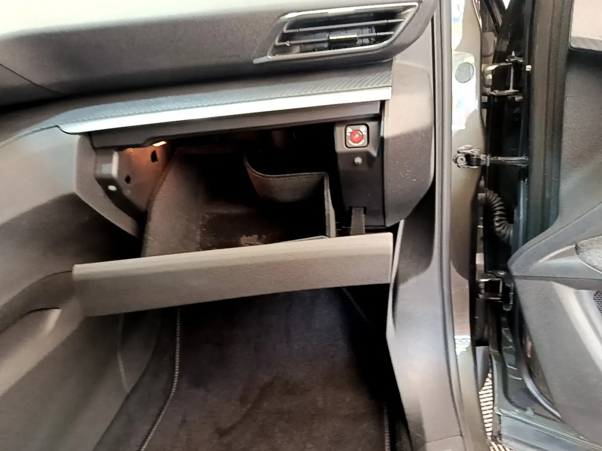 Vue rapprochée de la boîte à gants ouverte côté passager du Peugeot 3008 gris foncé, intérieur noir.